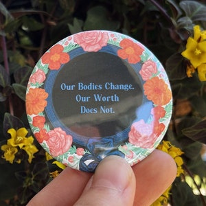 Peut inclure: Un bouton rond avec un motif floral et le texte "Our Bodies Change. Our Worth Does Not."
