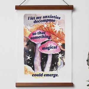 Può includere: Un poster da parete con binari in legno scuro e un cordino nero, caratterizzato da un'illustrazione ad acquerello di due funghi rosa, foglie arancioni e stelle bianche. Il testo recita: I let my anxieties decompose so that something magical could emerge.