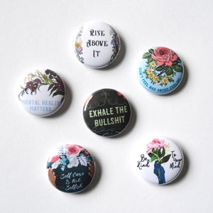May include: Six round floral-themed buttons with inspirational messages. The messages include "Rise Above It", "Mental Health Matters", "Exhale the Bullshit", "Self Care is Not Selfish", "Don't Feel Bad About Feeling", and "Be Kind to Your Mind".
