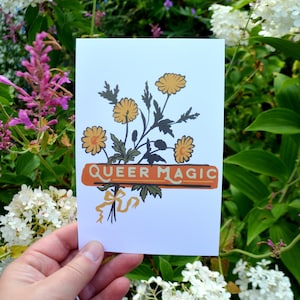 May include: A white card with a bouquet of yellow flowers and a banner that reads "Queer Magic".