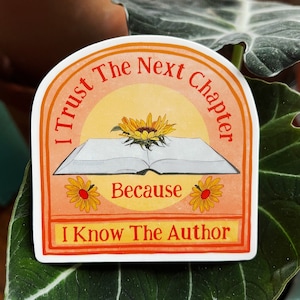 May include: A sticker with a peach background and a yellow sun. The sticker says "I trust the next chapter because I know the author." There is a book with a sunflower on top of it and two smaller sunflowers on either side of the text "because".