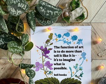 May include: A white print with a floral design and a quote by bell hooks: "The function of art is to do more than tell it like it is - it's to imagine what is possible."