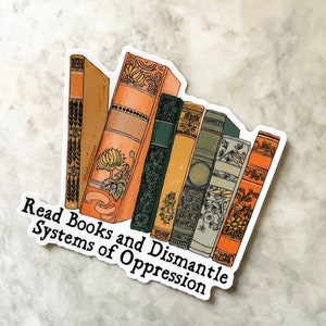 May include: A sticker with a stack of vintage books with ornate covers and the text "Read Books and Dismantle Systems of Oppression".