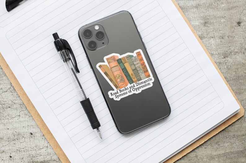 May include: A sticker with a stack of vintage books and the text "Read Books and Dismantle Systems of Oppression". The sticker is on a gray phone case.