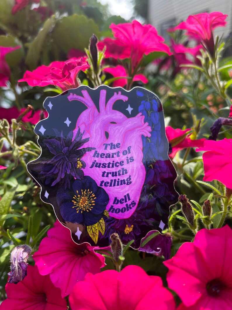 Puede incluir: Una pegatina con un coraz&oacute;n rosa y un dise&ntilde;o floral. El texto en la pegatina dice "The heart of justice is truth telling bell hooks".
