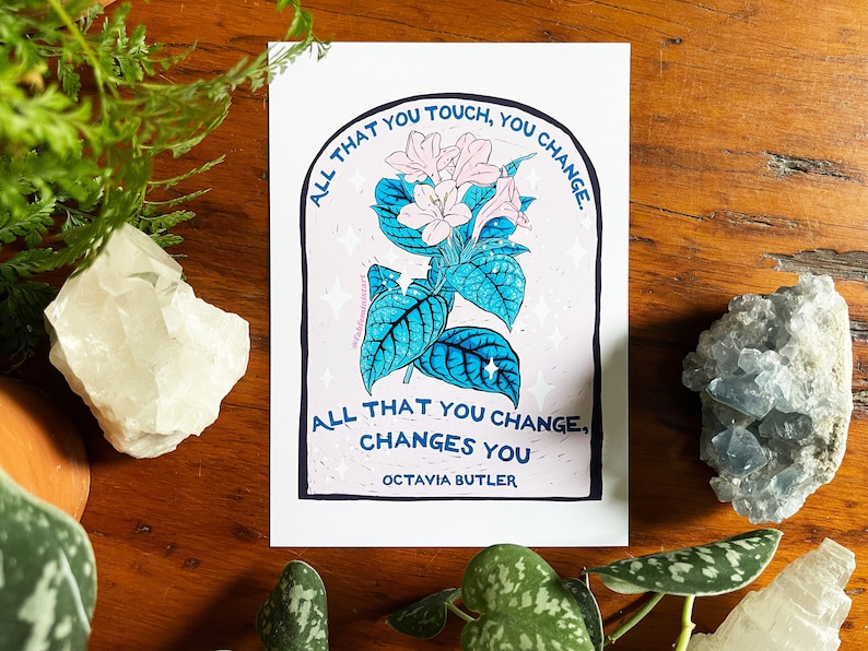 Peut inclure: Une illustration d'une fleur rose et bleue avec la citation "Tout ce que vous touchez, vous changez. Tout ce que vous changez, vous change. Octavia Butler" imprim&eacute;e sur un fond blanc.