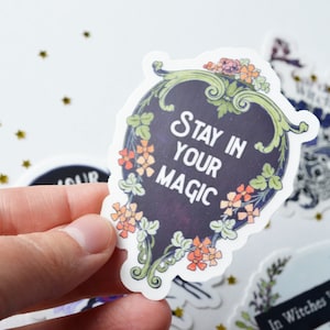 May include: A black and white sticker with a floral border and the text "Stay in your magic".