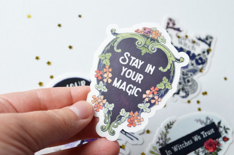May include: A black and white sticker with a floral border and the text "Stay in your magic".