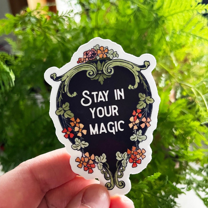 May include: A black and white sticker with a floral design and the text "Stay in your magic".