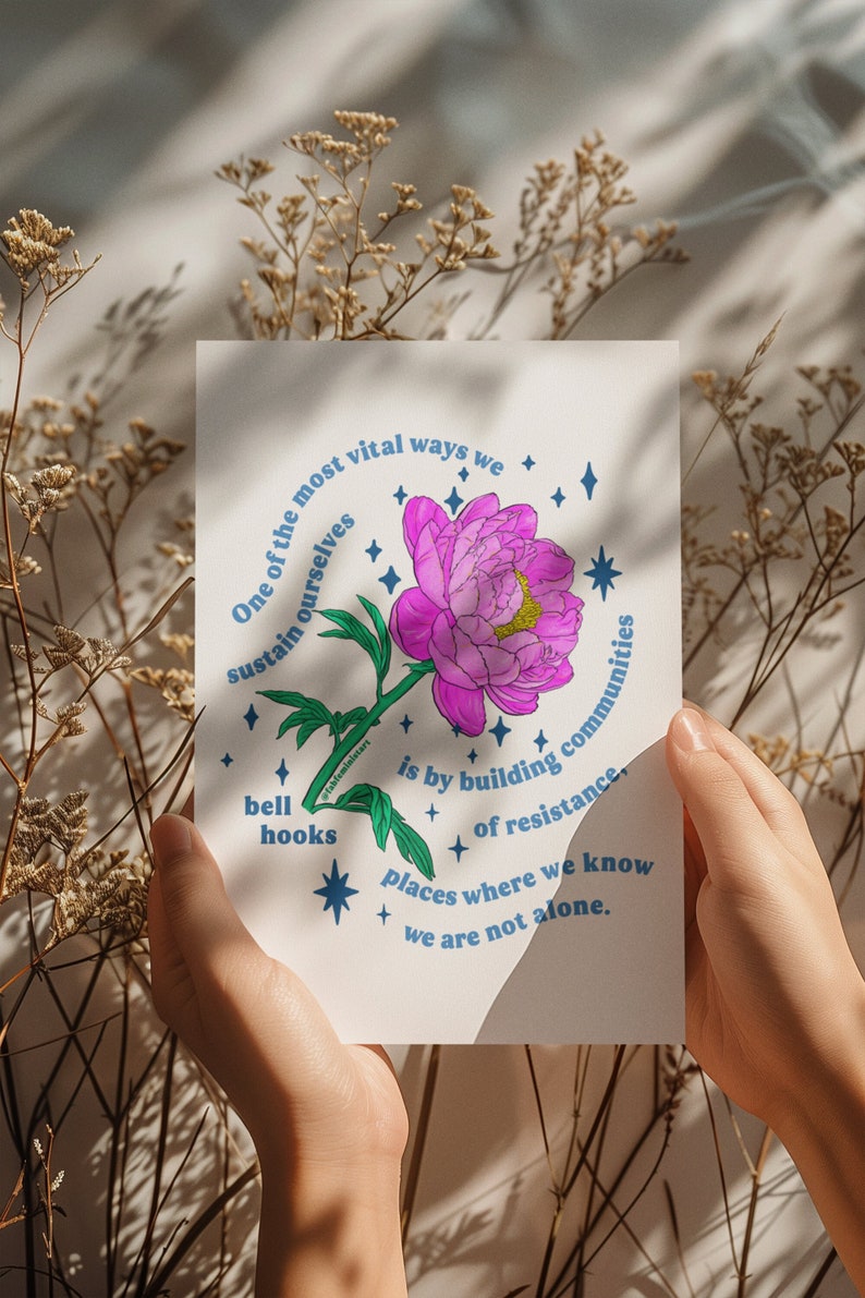 May include: A white card with blue text and a pink flower illustration. The text reads "One of the most vital ways we sustain ourselves is by building communities of resistance, places where we know we are not alone."