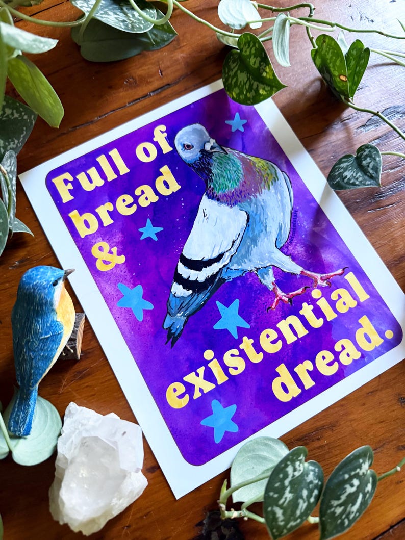 K&ouml;nnte beinhalten: Ein rechteckiger Kunstdruck mit einer Taube vor einem leuchtend violetten Hintergrund mit hellblauen Sternen. Der Text lautet Full of bread & existential dread. Die Taube hat graue, wei&szlig;e und schillernd gr&uuml;ne Federn sowie rosa F&uuml;&szlig;e.