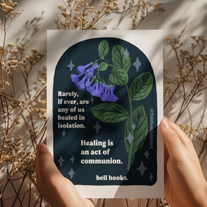 May include: A dark blue background with a white border features a purple flower with green leaves and white stars. The text reads "Rarely, if ever, are any of us healed in isolation. Healing is an act of communion. bell hooks."