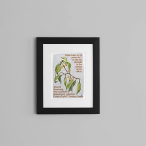 K&ouml;nnte beinhalten: Ein gerahmter Druck mit einer botanischen Illustration eines gr&uuml;nen, belaubten Zweigs mit kleinen gelben Bl&uuml;ten. Der Druck zeigt ein Zitat dar&uuml;ber, m&auml;chtig zu sein und seine St&auml;rke im Dienste seiner Vision einzusetzen. Das Zitat wird Andre Lorde zugeschrieben.