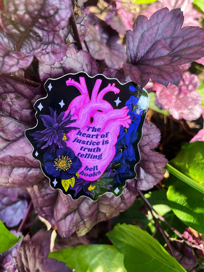 Puede incluir: Una pegatina en forma de coraz&oacute;n con un coraz&oacute;n anat&oacute;mico rosa y dise&ntilde;os florales negros. El texto dice "The heart of justice is truth telling bell hooks".