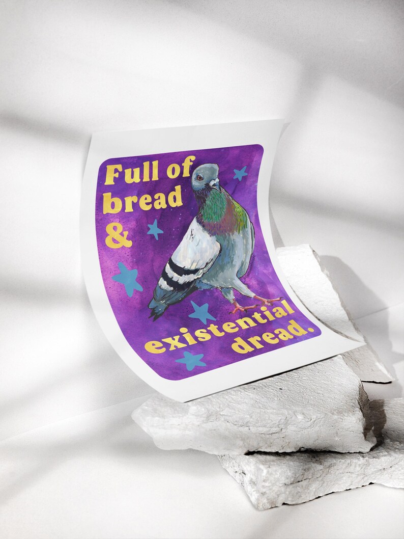 K&ouml;nnte beinhalten: Ein rechteckiger Kunstdruck mit einer grauen Taube mit schillernden Halsfedern vor einem violetten Hintergrund. Der Text lautet Full of bread & existential dread in gelben Buchstaben, akzentuiert durch hellblaue Sterne im Design.