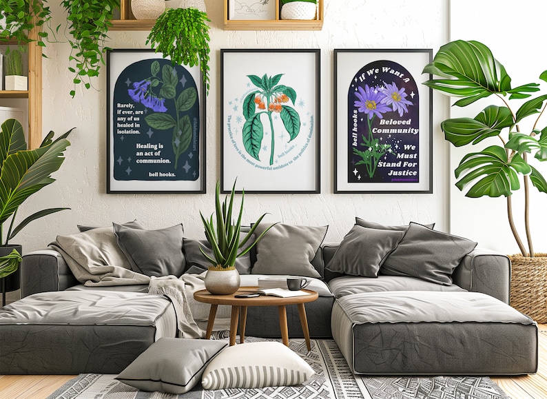 May include: Three framed art prints with floral illustrations and inspirational quotes. The prints are hanging on a white wall above a gray sectional sofa. The quotes are "Rarely, if ever, are any of us healed in isolation. Healing is an act of communion. bell hooks."  "The practice of love is the most powerful antidote to the violence of our times. bell hooks." and "If we want a Beloved Community, We Must Stand For Justice."