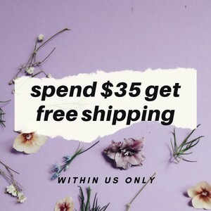 May include: A white torn paper note with the text "spend $35 get free shipping" on a purple background with small white and purple flowers scattered around the note. The text "WITHIN US ONLY" is below the note.