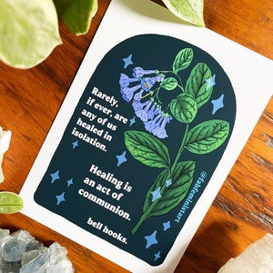 May include: A dark blue and green illustration of a flower with blue blossoms and white stars. The text reads "Rarely, if ever, are any of us healed in isolation. Healing is an act of communion. bell hooks."