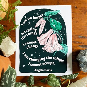 May include: A black and green print with a quote by Angela Davis: "I am no longer accepting the things I cannot change. I am changing the things I cannot accept."