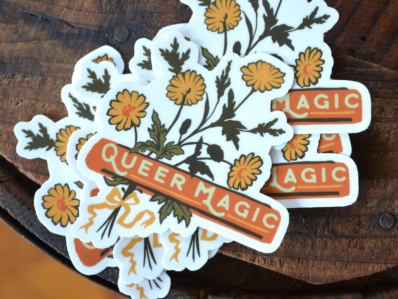 Puede incluir: Un conjunto de pegatinas con un ramo de flores amarillas con hojas verdes y una pancarta que dice "Queer Magic". Las pegatinas tienen un estilo vintage con detalles en naranja y marr&oacute;n.