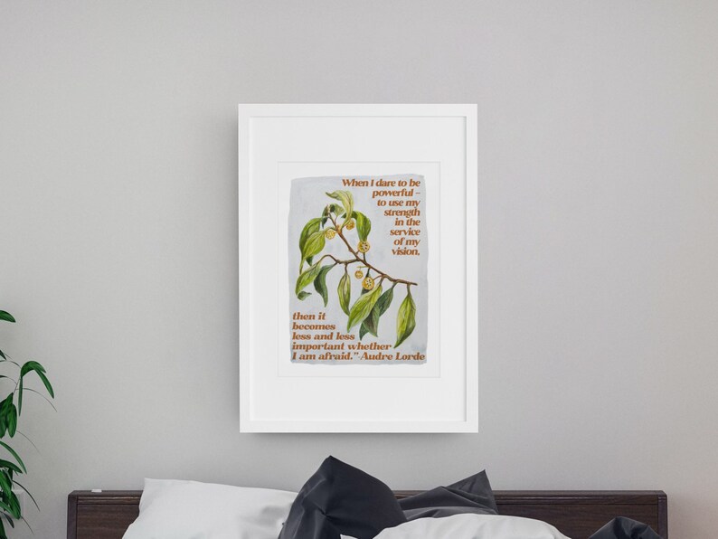K&ouml;nnte beinhalten: Ein gerahmter Druck mit einer botanischen Illustration eines gr&uuml;nen, belaubten Zweigs mit gelben Bl&uuml;ten. Der Druck zeigt ein Zitat von Audre Lorde: "Wenn ich es wage, m&auml;chtig zu sein - meine Kraft im Dienste meiner Vision einzusetzen. Dann wird es immer weniger wichtig, ob ich Angst habe."