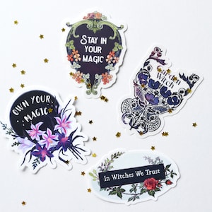May include: Four stickers with floral designs and inspirational quotes. The stickers feature black backgrounds with white text. The quotes are "Own Your Magic", "Stay In Your Magic", "Garden Witch", and "In Witches We Trust".