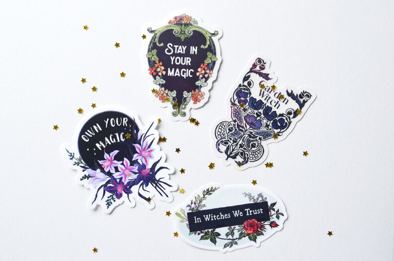 May include: Four stickers with floral designs and inspirational quotes. The stickers feature black backgrounds with white text. The quotes are "Own Your Magic", "Stay In Your Magic", "Garden Witch", and "In Witches We Trust".