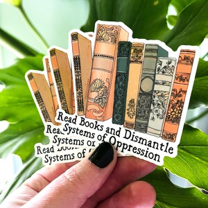 May include: A sticker with a stack of vintage books and the text "Read Books and Dismantle Systems of Oppression".