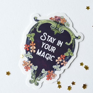 May include: A sticker with a floral design and the text "Stay in your magic" in a white font on a dark blue background.