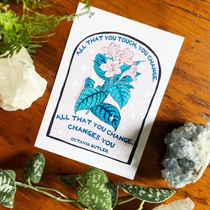 Peut inclure: Une impression rose et bleue avec une citation d'Octavia Butler : "Tout ce que vous touchez, vous changez. Tout ce que vous changez, vous change."