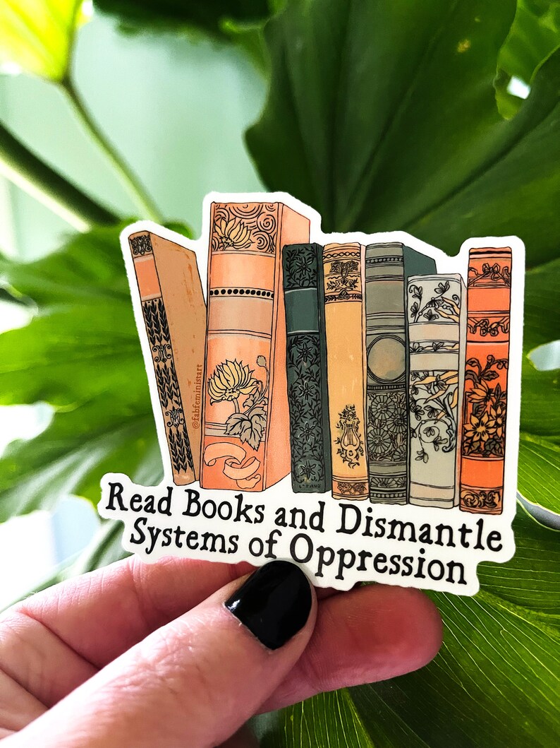 May include: A sticker with a stack of illustrated books and the text "Read Books and Dismantle Systems of Oppression".