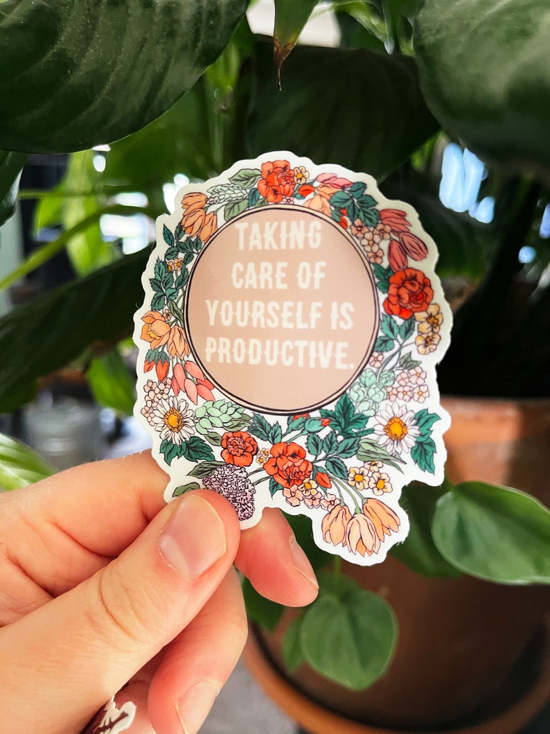 May include: A white sticker with a floral border and a pink circle in the centre. The text inside the circle reads "Taking care of yourself is productive."