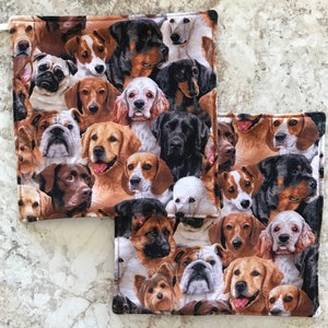 May include: A set of two brown and white fabric pot holders with a pattern of various dog breeds. The pot holders are square shaped and have a stitched border.