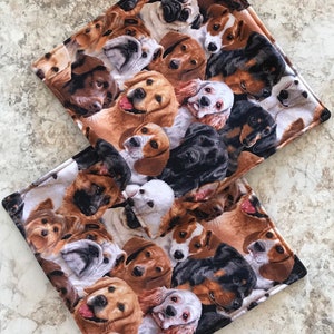 May include: Two brown and black fabric placemats with a pattern of various dog breeds. The placemats are made of a soft, plush fabric and feature a variety of dog breeds, including golden retrievers, poodles, and bulldogs.
