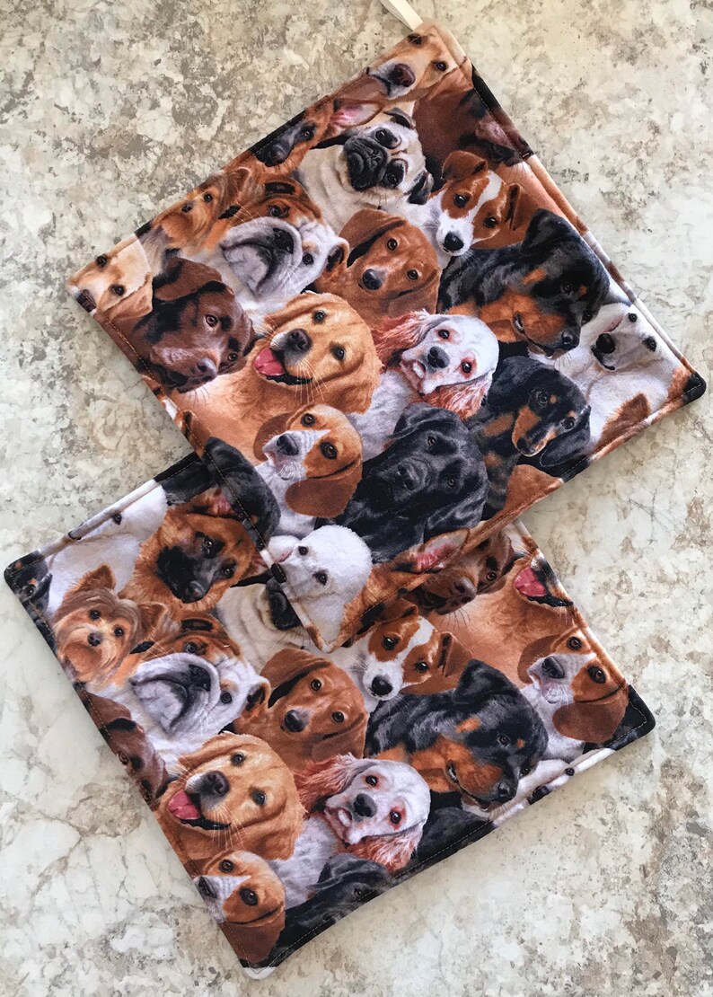 May include: Two brown and black fabric placemats with a pattern of various dog breeds. The placemats are made of a soft, plush fabric and feature a variety of dog breeds, including golden retrievers, poodles, and bulldogs.