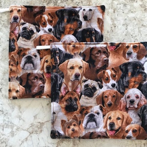 May include: Two brown and beige pot holders with a pattern of various dog breeds. The pot holders are made of fabric and have a white loop for hanging.
