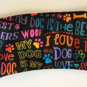 May include: Black fabric with colorful text and paw prints. The text includes phrases like "My Dog is the Best," "I Love My Dog," and "Woof." A black loop is attached to the side.