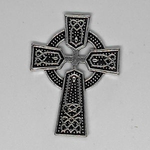 May include: A silver-colored Celtic cross pendant with intricate knotwork and dotted patterns. The cross features a circular center and flared arms, showcasing detailed design elements. The pendant is likely made of metal and is suitable for jewelry.