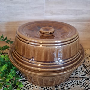 May include: A brown ceramic casserole dish with a lid. The dish has a ribbed design and the lid has a knob on top.