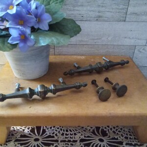 May include: Three antique brass cabinet knobs and two drawer pulls with ornate designs. The knobs are round and the pulls are long and slender.