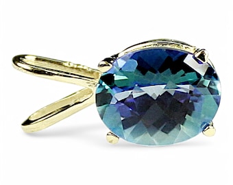 May include: A gold pendant featuring a large oval-shaped blue gemstone with a green hue. The pendant has a simple, elegant design.