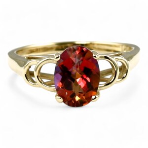 May include: A gold ring with an oval-shaped red gemstone set in a delicate, twisted band.