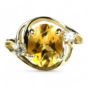 May include: A gold ring with a large oval-shaped topaz gemstone and two smaller round-shaped diamonds on the band.