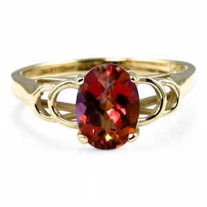 May include: A gold ring with an oval-shaped red gemstone set in a delicate, twisted band.