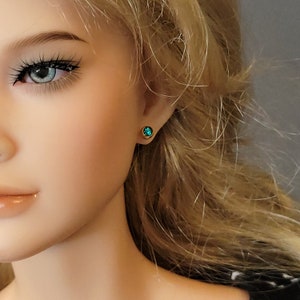 May include: A pair of gold stud earrings with small, round, teal gemstones.