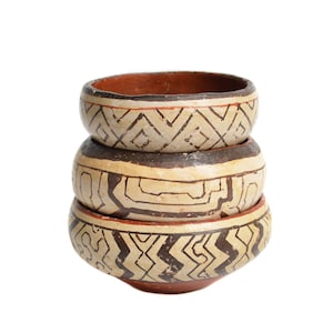 Op de afbeelding: Drie gestapelde keramische kommen met geometrische patronen in bruin en wit. De kommen zijn in elkaar genest.