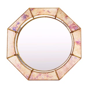 May include: Octagonal mirror with a pink and purple iridescent glass frame. The frame has a gold trim and a decorative pattern.