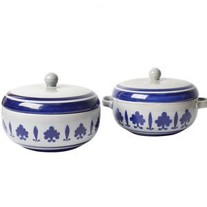 May include: Two ceramic serving bowls with lids. The bowls are white with blue trim and a repeating pattern of stylized trees and leaves. Each bowl has a grey knob on the lid.