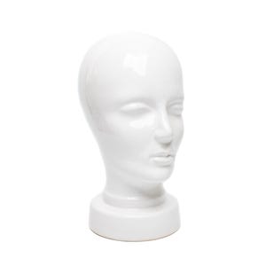 Op de afbeelding: Een glanzende witte keramische mannequinhoofd met een gedetailleerd gezicht, gesloten ogen, een duidelijke neus en volle lippen. De kop staat op een korte, cirkelvormige basis, perfect voor het presenteren van pruiken, hoeden of sieraden. Het ontwerp is glad en elegant.