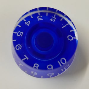 Może przedstawiać: Niebieski plastikowy gałka z białymi numerami od 0 do 10 wokół krawędzi.